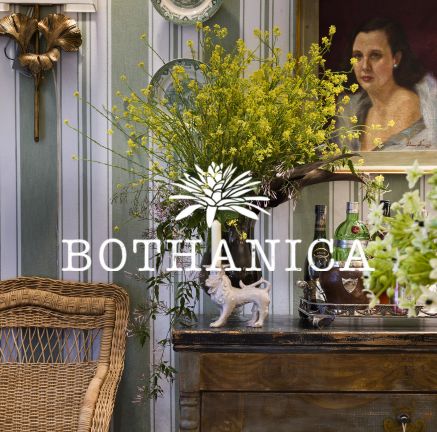 móvel rústico com vaso de flor e a logo Bothanica